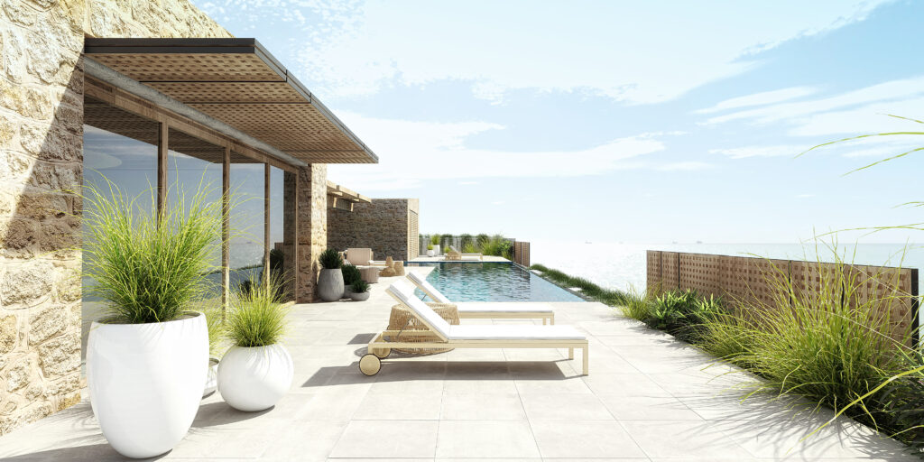 External view of the stone house showing a pool with sunbeds by a beautiful stone house.